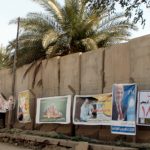 Campaign posters line a concrete blast wall in Baghdad.