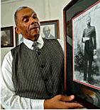 Photo: The Rev. L. Jerome Fowler, great-nephew of Henry Vinton Plummer and associate to the pastor at St. Paul Baptist Church, holds a portrait of Plummer at the church, for which Plummer was pastor. 