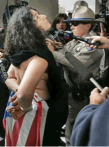 Photo Sheryl Glaser of Albion, Calif., has a shirt put over her bare upper body after she was arrested by CHP officers at the state Capitol Monday. (Robert Durell / LAT)
