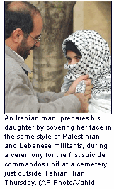 An Iranian man, prepares his daughter by covering her face in the same style of Palestinian and Lebanese militants, during a ceremony for the first suicide commandos unit at a cemetery just outside Tehran, Iran, Thursday. (AP Photo/Vahid Salemi)