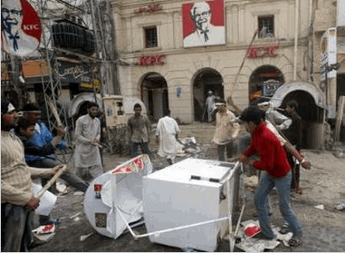 Protesters wreck KFC property before setting fire to the building during a rally in Lahore February 14, 2006. Police used tear gas to drive out students who stormed into Islamabad's diplomatic enclave on Tuesday and protesters attacked Western businesses in Pakistan's most violent reaction yet to cartoons of the Prophet Mohammad. REUTERS/Mian Khursheed