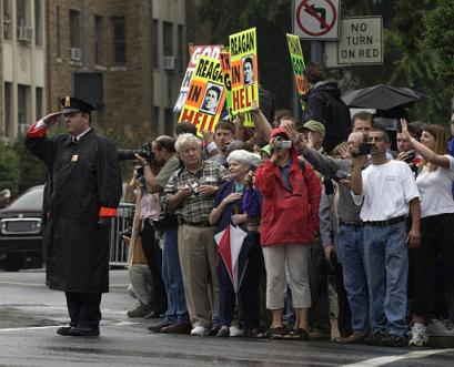 A police officer salutes in front of pro and anti-Ronald Reagan (news - web sites) groups near the National Cathedral in Washington Friday, June 11, 2004 prior to funeral services for the former president. (AP Photo/Eric Gay)